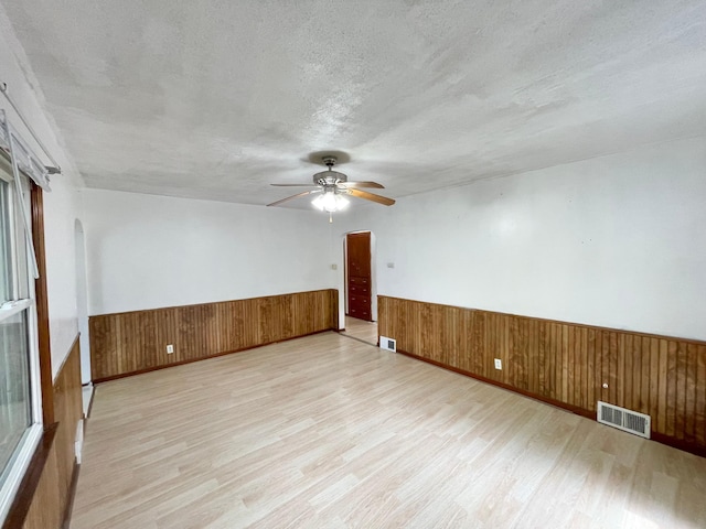 111 Park Ave, Springfield, MN 56087 - empty room with wainscoting, light wood-style flooring, a ceiling fan, wood walls, and a textured ceiling