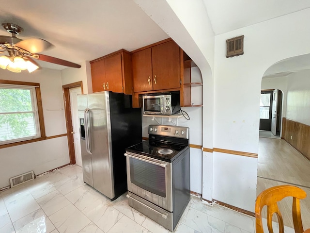 111 Park Ave, Springfield, MN 56087 - kitchen with stainless steel appliances, arched walkways, a ceiling fan, brown cabinets, and light marble finish flooring