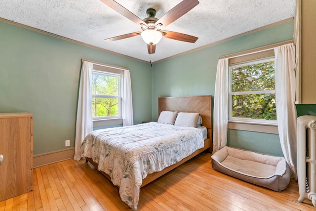 842 2nd St NW, Rochester, MN 55901 - bedroom featuring crown molding, radiator heating unit, light wood-type flooring, a ceiling fan, and baseboards