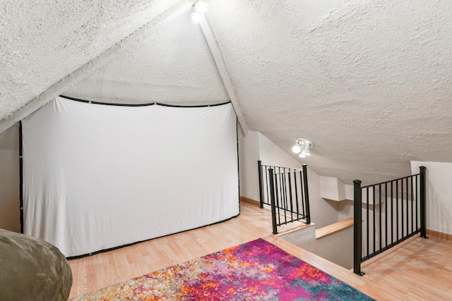 842 2nd St NW, Rochester, MN 55901 - additional living space featuring wood finished floors, a textured ceiling, vaulted ceiling, and baseboards