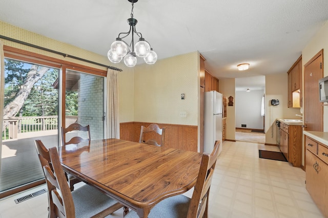 11748 Bittersweet St NW, Coon Rapids, MN 55433 - dining space with light floors, a chandelier, wainscoting, and wood walls