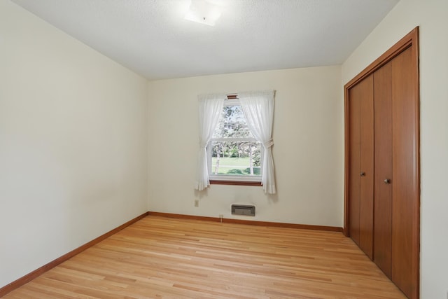 11748 Bittersweet St NW, Coon Rapids, MN 55433 - unfurnished bedroom with light wood finished floors, a closet, baseboards, and a wall unit AC