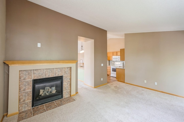 1005 Providence Dr, Shakopee, MN 55379 - unfurnished living room featuring light carpet, vaulted ceiling, baseboards, a fireplace, and a sink