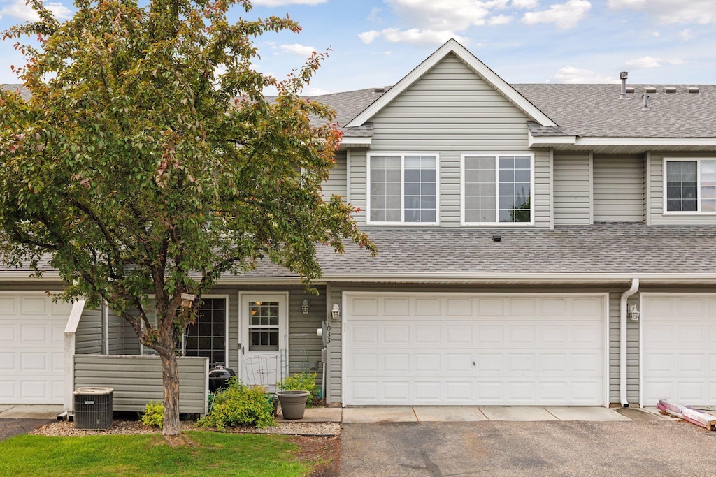 11033 Douglas Ln N, Champlin, MN 55316 - multi unit property with a shingled roof, asphalt driveway, central air condition unit, and an attached garage