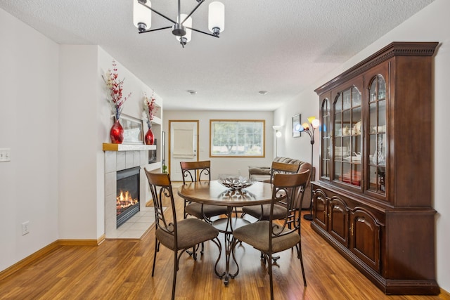 16480 Elm Creek Ln, Lakeville, MN 55044 - dining space featuring a tile fireplace, a textured ceiling, a chandelier, and light wood-type flooring