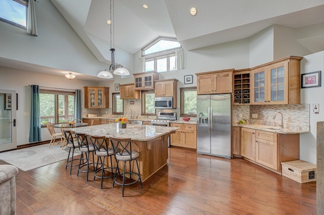 1167 56th St, Hudson, WI 54016 - kitchen with appliances with stainless steel finishes, high vaulted ceiling, a kitchen breakfast bar, a center island, and light stone countertops