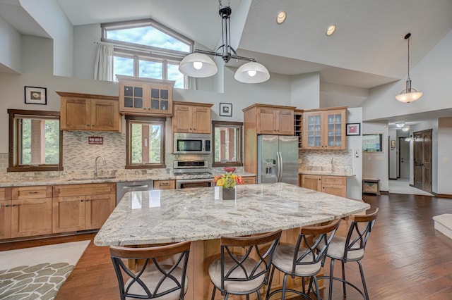 1167 56th St, Hudson, WI 54016 - kitchen featuring stainless steel appliances, high vaulted ceiling, a kitchen island, glass insert cabinets, and a kitchen breakfast bar