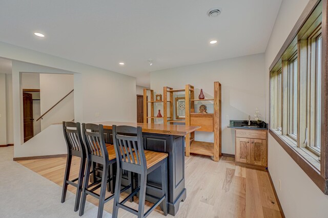 1167 56th St, Hudson, WI 54016 - dining room featuring light wood-style floors, bar with sink, recessed lighting, and stairway