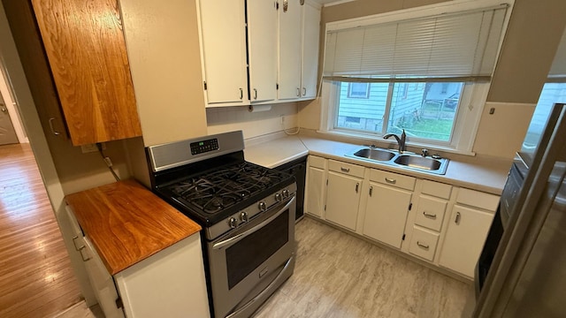 707 11th Ave SE, Rochester, MN 55904 - kitchen with stainless steel range with gas stovetop, light wood finished floors, a sink, light countertops, and white cabinetry