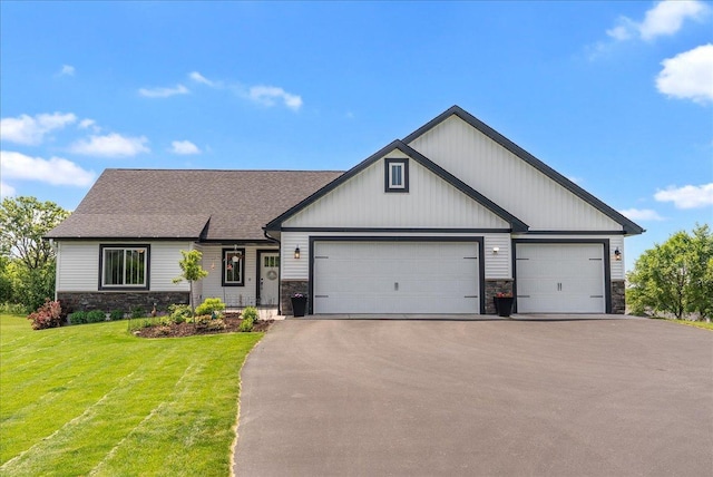 1609 75th Ave, Hammond, WI 54015 - view of front facade with stone siding, driveway, a front yard, a garage, and a shingled roof