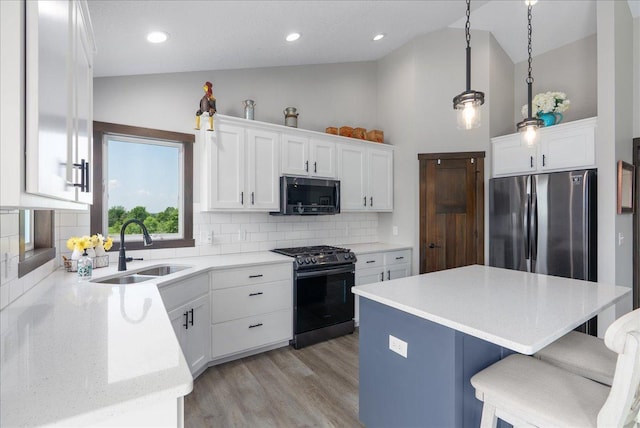 1609 75th Ave, Hammond, WI 54015 - kitchen featuring appliances with stainless steel finishes, vaulted ceiling, tasteful backsplash, a kitchen bar, and light wood-style flooring