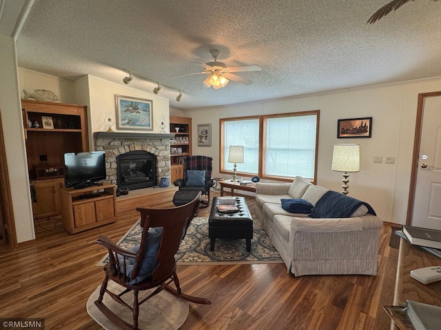 18755 Cassie Ln, Pokegama Twp, MN 55063 - living area featuring a textured ceiling, ceiling fan, dark wood finished floors, a stone fireplace, and track lighting