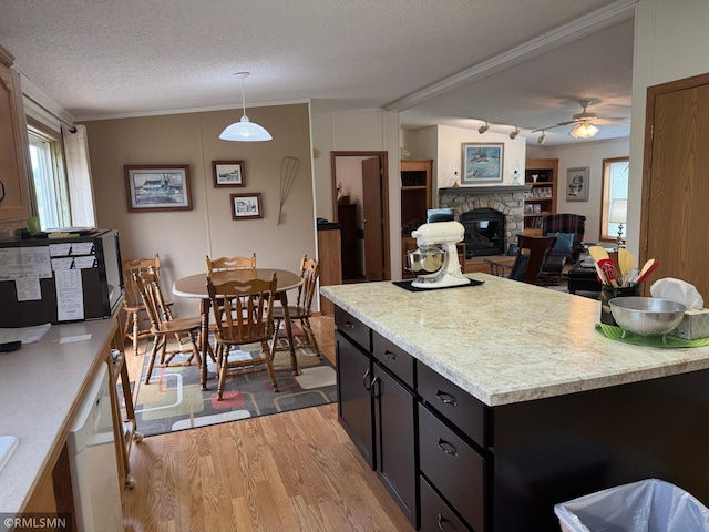 18755 Cassie Ln, Pokegama Twp, MN 55063 - kitchen with light wood finished floors, a textured ceiling, light countertops, a stone fireplace, and a ceiling fan