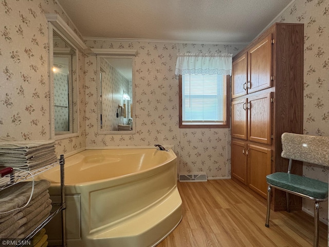 18755 Cassie Ln, Pokegama Twp, MN 55063 - bathroom featuring wood finished floors, a bath, wallpapered walls, a textured ceiling, and ornamental molding