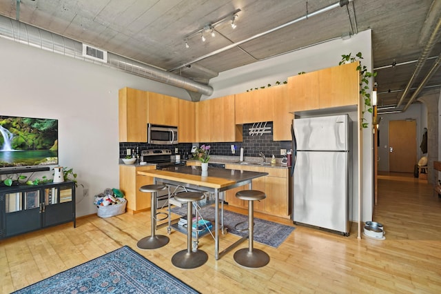 748 3rd St N Unit 504, Minneapolis, MN 55401 - kitchen featuring stainless steel appliances, light wood-style floors, tasteful backsplash, light countertops, and a sink