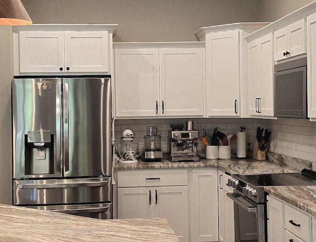 1300 Event Center Dr NE # 23, Bemidji, MN 56601 - kitchen featuring appliances with stainless steel finishes, white cabinets, tasteful backsplash, and light stone countertops