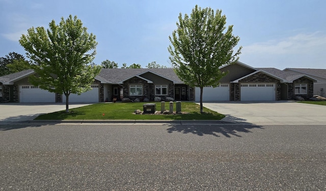 1300 Event Center Dr NE # 23, Bemidji, MN 56601 - view of front of home featuring driveway, a garage, stone siding, and a front yard