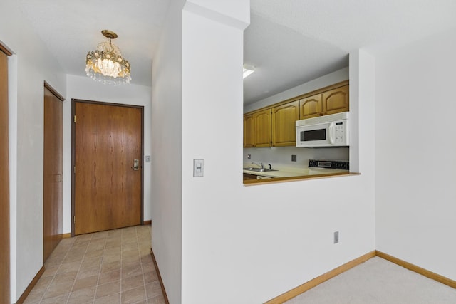 1425 28th St Unit 201, Minneapolis, MN 55408 - kitchen with white microwave, a sink, range, a chandelier, and baseboards