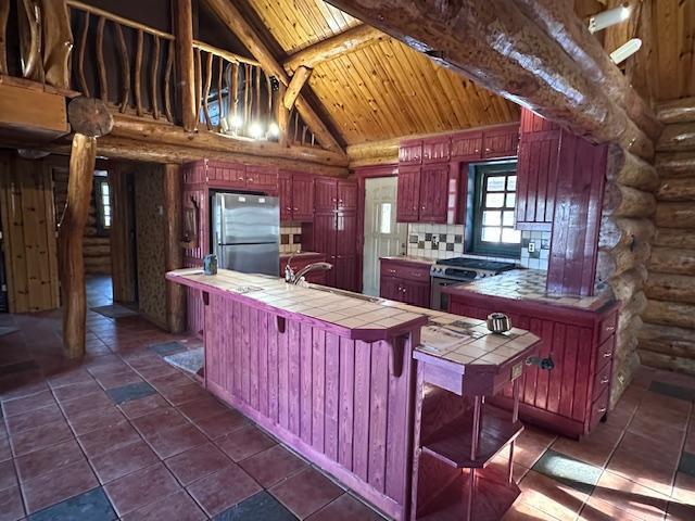 3547 Norway Ln, Ely, MN 55731 - kitchen with appliances with stainless steel finishes, tile counters, rustic walls, reddish brown cabinets, and high vaulted ceiling