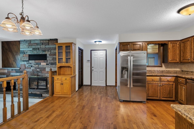 829 Cummings Ln, Saint Cloud, MN 56301 - kitchen featuring stainless steel fridge with ice dispenser, a textured ceiling, a chandelier, brown cabinetry, and wood finished floors