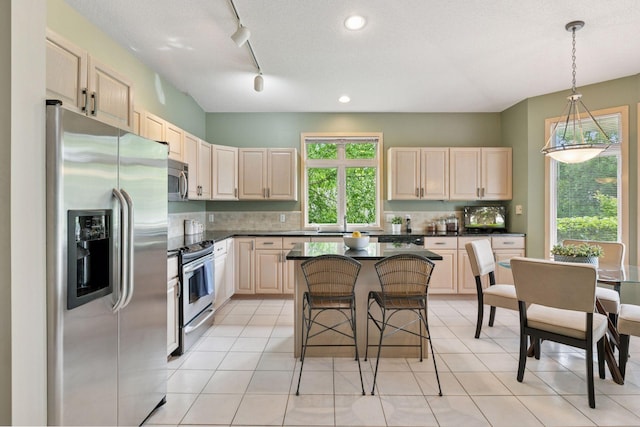 8910 Hilloway Rd, Eden Prairie, MN 55347 - kitchen featuring appliances with stainless steel finishes, dark countertops, a kitchen bar, light brown cabinetry, and track lighting