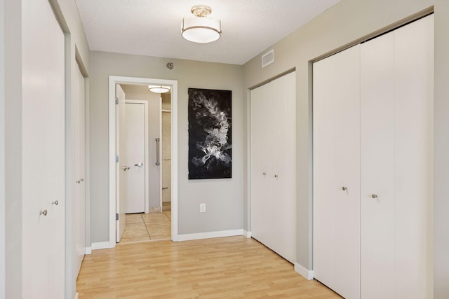 52 Groveland Ter Unit A402, Minneapolis, MN 55403 - unfurnished bedroom featuring two closets, light wood-style floors, baseboards, connected bathroom, and a textured ceiling
