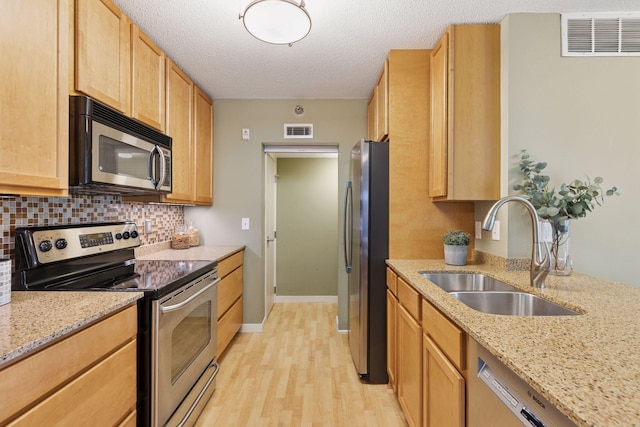 52 Groveland Ter Unit A402, Minneapolis, MN 55403 - kitchen with stainless steel appliances, a sink, light wood finished floors, backsplash, and light stone countertops