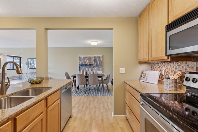 52 Groveland Ter Unit A402, Minneapolis, MN 55403 - kitchen with stainless steel appliances, a sink, decorative backsplash, light wood-type flooring, and light stone countertops