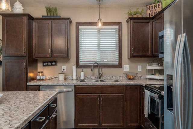 641 Beverly St, Wanamingo, MN 55983 - kitchen featuring appliances with stainless steel finishes, a sink, dark brown cabinetry, decorative light fixtures, and light stone countertops