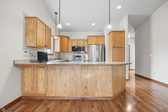4388 52nd St S, Fargo, ND 58104 - kitchen with appliances with stainless steel finishes, a peninsula, wood finished floors, light countertops, and decorative light fixtures
