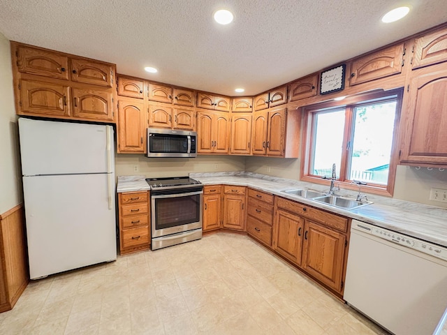 731 Grove Ave, Bird Island, MN 55310 - kitchen with appliances with stainless steel finishes, a sink, a textured ceiling, light countertops, and brown cabinetry