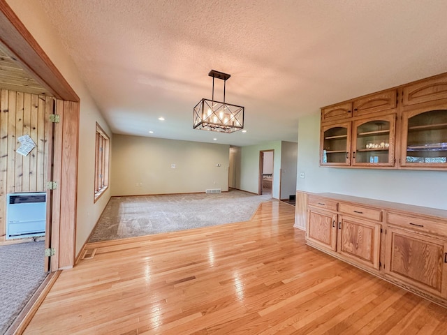 731 Grove Ave, Bird Island, MN 55310 - unfurnished dining area with heating unit, light wood finished floors, baseboards, a textured ceiling, and light colored carpet