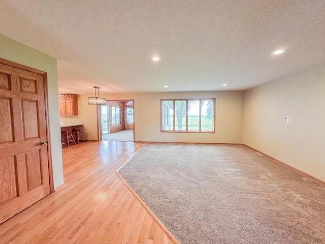 731 Grove Ave, Bird Island, MN 55310 - unfurnished living room featuring recessed lighting, a textured ceiling, light wood-style flooring, baseboards, and a chandelier