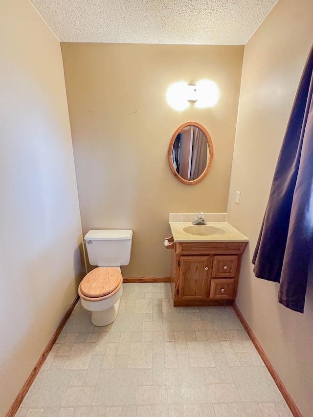 731 Grove Ave, Bird Island, MN 55310 - half bathroom with toilet, vanity, a textured ceiling, baseboards, and tile patterned floors