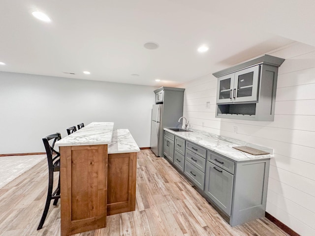 731 Grove Ave, Bird Island, MN 55310 - kitchen with gray cabinetry, freestanding refrigerator, light stone countertops, a center island, and recessed lighting