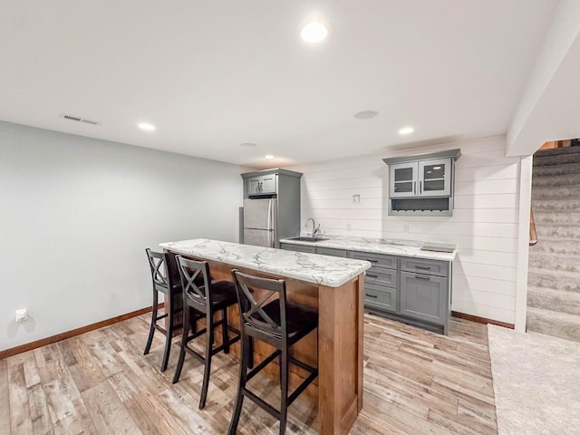 731 Grove Ave, Bird Island, MN 55310 - kitchen featuring gray cabinetry, freestanding refrigerator, a kitchen breakfast bar, light wood-type flooring, and recessed lighting
