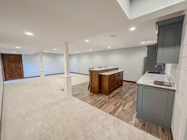 731 Grove Ave, Bird Island, MN 55310 - kitchen featuring a sink, a kitchen island, freestanding refrigerator, light wood-style flooring, and recessed lighting