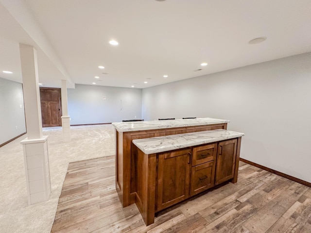 731 Grove Ave, Bird Island, MN 55310 - kitchen with a kitchen island, recessed lighting, baseboards, light wood-type flooring, and light stone countertops