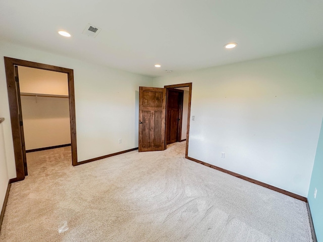 731 Grove Ave, Bird Island, MN 55310 - unfurnished bedroom featuring baseboards, recessed lighting, light colored carpet, and a walk in closet