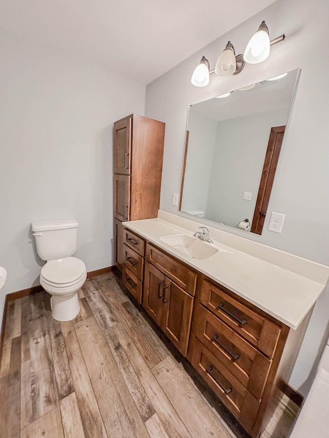 731 Grove Ave, Bird Island, MN 55310 - half bathroom featuring toilet, vanity, and wood finished floors