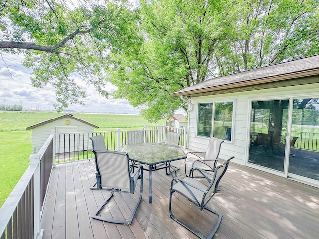 731 Grove Ave, Bird Island, MN 55310 - deck featuring outdoor dining space, a lawn, an outbuilding, and a rural view