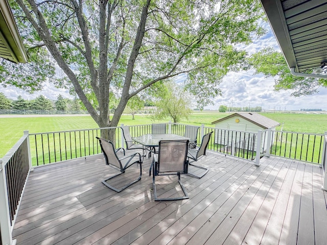 731 Grove Ave, Bird Island, MN 55310 - deck featuring outdoor dining space, a lawn, an outbuilding, and a view of countryside