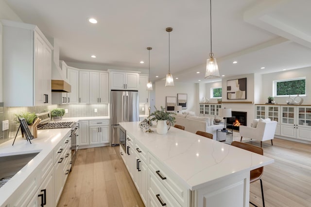 4804 12th Ave S, Minneapolis, MN 55417 - kitchen featuring stainless steel appliances, a glass covered fireplace, a kitchen island, light wood-style flooring, and backsplash