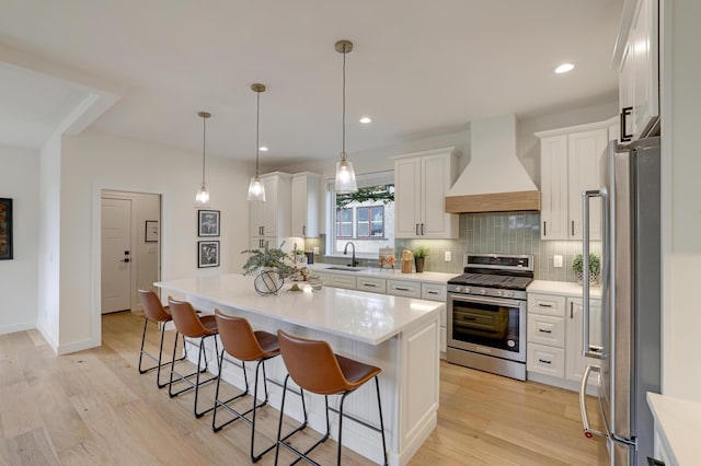4804 12th Ave S, Minneapolis, MN 55417 - kitchen featuring stainless steel appliances, custom exhaust hood, a kitchen breakfast bar, a sink, and light wood-style flooring