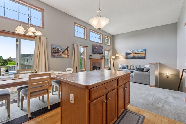 9741 Saint Andrews Dr, Elko New Market, MN 55020 - kitchen featuring light wood-type flooring, a kitchen island, a glass covered fireplace, and a chandelier