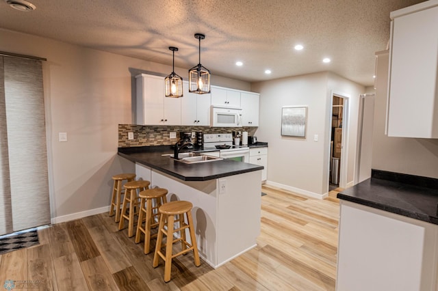 1156 42nd Ave W Unit A, West Fargo, ND 58078 - kitchen with white appliances, a sink, dark countertops, a peninsula, and light wood-style flooring
