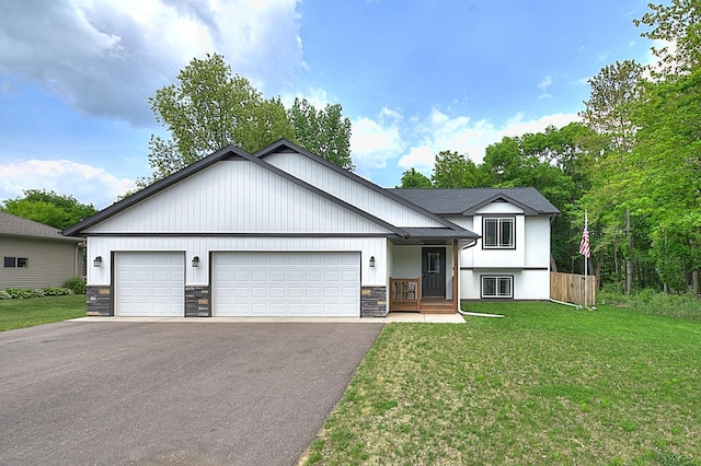 454 Roosevelt Dr, Dresser, WI 54009 - view of front of home featuring asphalt driveway, a front yard, an attached garage, and stone siding