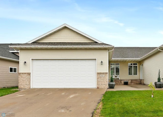 4467 53rd St S, Fargo, ND 58104 - view of front facade with concrete driveway, brick siding, an attached garage, roof with shingles, and a front lawn