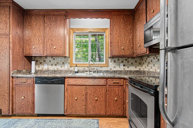 18905 Yalta St NE, East Bethel, MN 55092 - kitchen with appliances with stainless steel finishes, a sink, decorative backsplash, light wood-type flooring, and brown cabinets