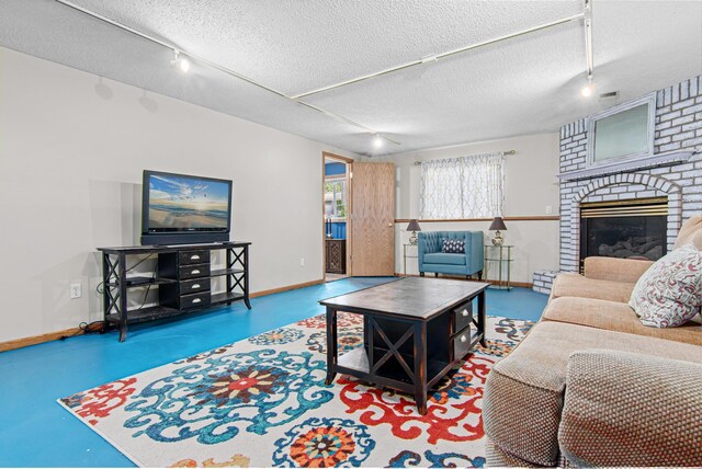 18905 Yalta St NE, East Bethel, MN 55092 - living room featuring track lighting, baseboards, a textured ceiling, a brick fireplace, and concrete flooring